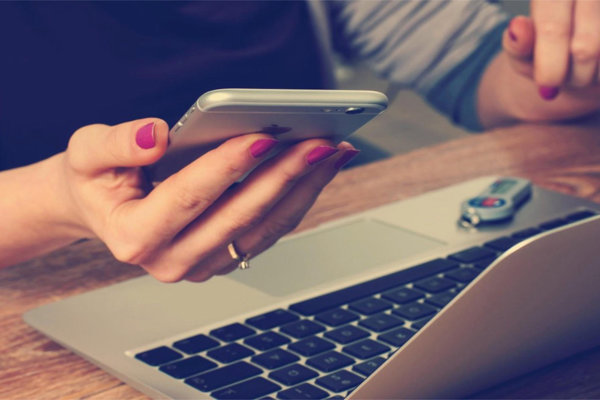 Closeup of hand holding phone over laptop